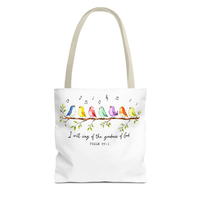 A white canvas tote bag with beige shoulder straps, featuring a colorful watercolor illustration of birds sitting on a branch with musical notes and the Bible verse 'I will sing of the goodness of God PSALM 89:1' printed below.