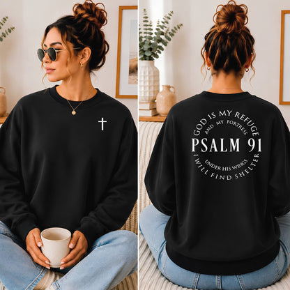 A woman shown from the front and back wearing a black crewneck sweatshirt. The front has a small white cross on the left chest, and the back features a large white graphic reading 'GOD IS MY REFUGE AND MY TRUST PSALM 91 UNDER HIS PROTECTION I WILL FIND SHELTER'.